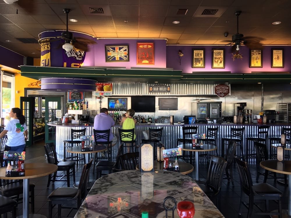 Interior of The Big Easy Cajun-Creole eatery featuring a bar area with colorful decor, tables set for dining, and patrons enjoying the atmosphere, reflecting the family-friendly and Mardi Gras theme of the restaurant.