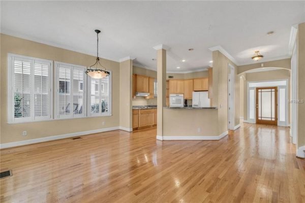 Spacious interior of 1125 Delaney Ave in Orlando, featuring hardwood floors, large windows with plantation shutters, and an open layout connecting the kitchen and living areas.