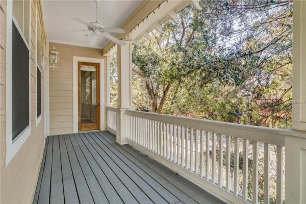 Porch view of 1125 Delaney Ave, Orlando, FL, featuring wooden flooring, white railings, and surrounding greenery, highlighting outdoor living space near Delaney Park.