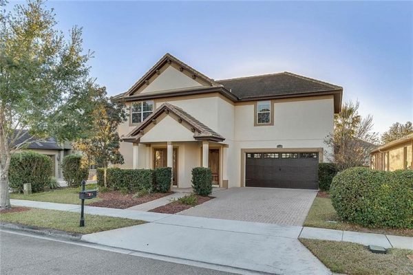 Exterior view of 11434 Brickyard Pond LN, Windermere, FL, showcasing a two-story home with a tile roof, landscaped front yard, and brick paver driveway, emphasizing its move-in ready status and proximity to local amenities.