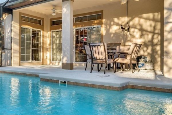 Backyard view featuring a screened pool and patio area with outdoor dining set, showcasing the inviting atmosphere of a Windermere home at 11434 Brickyard Pond LN.