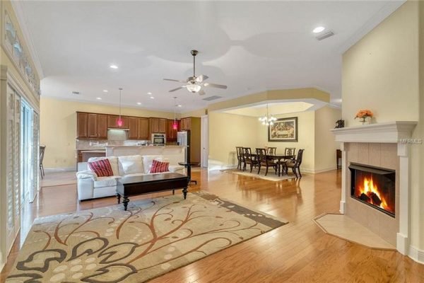 Spacious living area of Windermere home featuring hardwood floors, modern kitchen with pendant lighting, fireplace, and dining space, ideal for family gatherings.