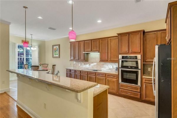 Modern kitchen interior with wooden cabinetry, granite countertops, and pendant lighting, showcasing the open floor plan of a Windermere home for sale.
