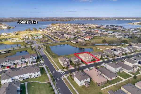 Aerial view of 15890 Citrus Grove Loop in Winter Garden, FL, highlighting the property near Johns Lake, surrounded by residential homes and ponds, emphasizing the premium lot location with no rear neighbors.