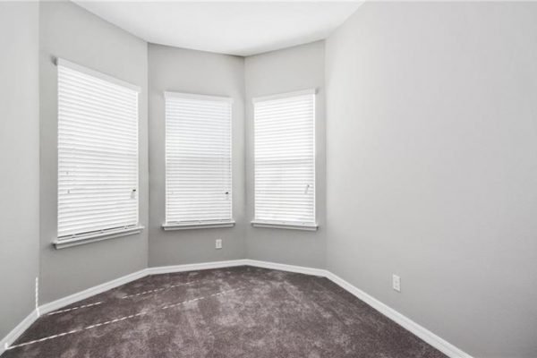Bright corner room with three windows, featuring gray walls and plush carpet, ideal for natural light in a 55+ community home at 2192 Antilles Club Dr, Kissimmee, FL.