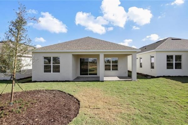 Newly constructed home exterior at 2192 Antilles Club Dr, Kissimmee, FL, featuring a modern design, large windows, and landscaped yard in a 55+ community.