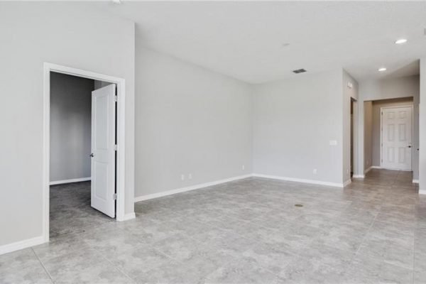 Spacious interior of a newly constructed home at 2192 Antilles Club Dr, Kissimmee, FL, featuring gray walls, tile flooring, and an open layout, ideal for a 55+ community lifestyle.