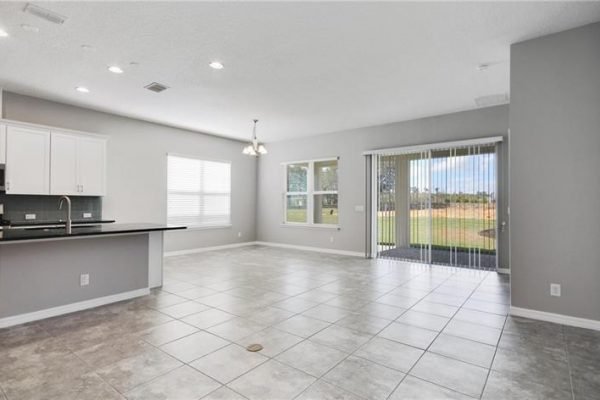 Spacious interior of 2192 Antilles Club Dr, Kissimmee, FL, featuring modern kitchen with island, open living area, large windows, and sliding glass doors leading to outdoor space in a desirable 55+ community.