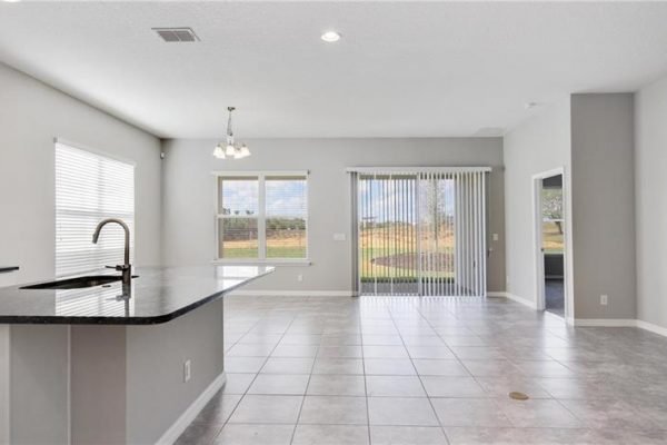 Spacious interior of a new home at 2192 Antilles Club Dr, Kissimmee, FL, featuring an open layout with tile flooring, modern kitchen island, and large windows providing natural light.