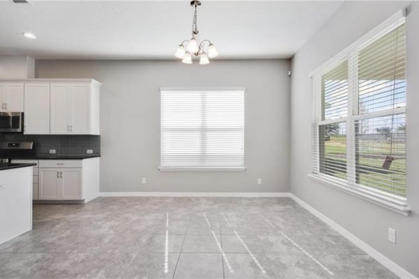Spacious interior of a newly built home at 2192 Antilles Club Dr, Kissimmee, featuring a modern kitchen with white cabinetry, large windows, and tile flooring, ideal for active adults in a 55+ community.