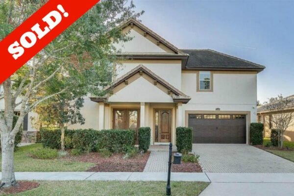 Sold sign on a two-story Windermere home with a brick paver driveway, landscaped front yard, and garage, representing a successful real estate transaction.