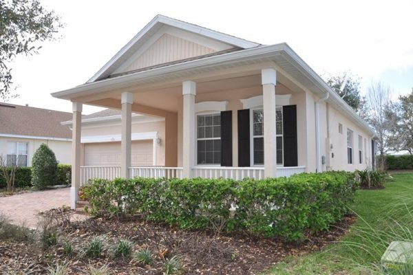 Front view of a single-family home at 117 Crepe Myrtle Dr, Groveland, FL, featuring a covered porch, landscaped yard, and brick paver driveway, highlighting the charm of the Trilogy over 55 community.