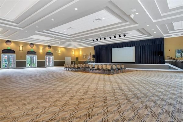 Spacious event hall in Trilogy, Groveland, FL, featuring elegant decor, stage area, and arranged seating, ideal for community gatherings and activities.