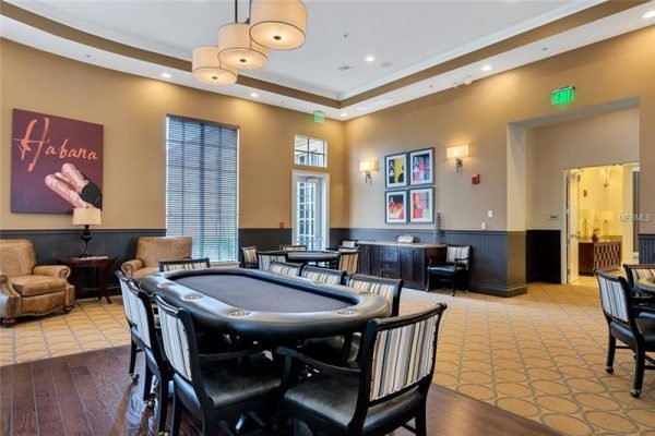 Interior of a luxurious community clubhouse featuring a poker table, comfortable seating, and decorative art, emphasizing the social atmosphere of Trilogy, a 55+ resort community in Central Florida.