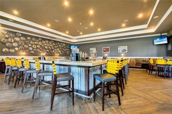 Modern bar area with yellow and black stools, granite countertop, and decorative wall plates, located in a luxurious over 55 community in Central Florida.