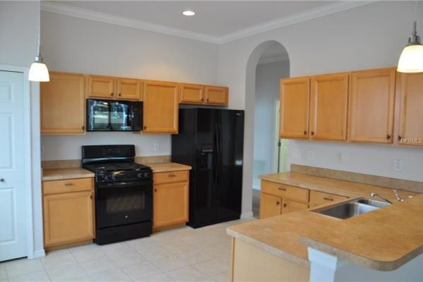Kitchen interior featuring wooden cabinetry, black appliances, and a spacious layout in a Groveland, FL home for sale at 117 Crepe Myrtle Dr.