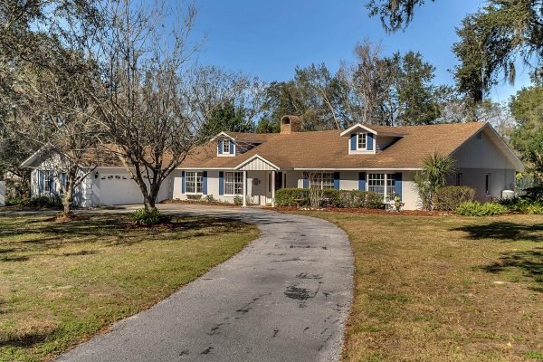 Single-story home at 1421 Crescent Lake Dr, Windermere, FL, featuring a circular driveway, mature landscaping, and a welcoming front porch, ideal for showcasing the spacious estate with pool and private tennis court.