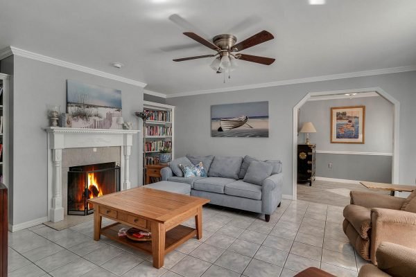 Cozy living room featuring a blue sofa, wooden coffee table, and a fireplace, with bookshelves and artwork on the walls, reflecting the inviting atmosphere of the Windermere estate at 1421 Crescent Lake Dr.