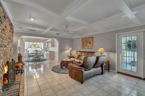 Cozy family room in Windermere, featuring leather seating, a stone fireplace, and a view of the dining area with natural light, highlighting the spacious layout and elegant decor.