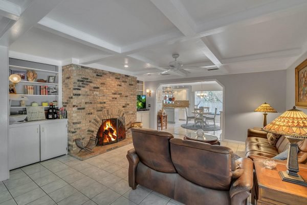Cozy family room featuring a stone fireplace, leather seating, built-in shelves, and an open layout leading to a dining area, ideal for entertaining in the Windermere estate at 1421 Crescent Lake Dr.