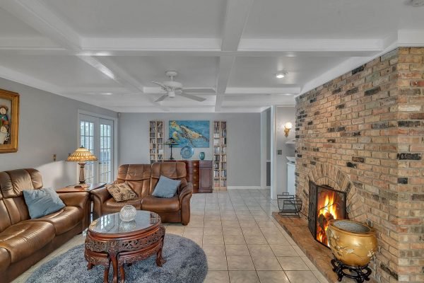 Cozy family room in Windermere, featuring leather sofas, a round coffee table, brick fireplace, and decorative art, highlighting spacious layout and inviting atmosphere.