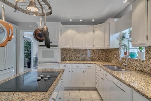 Modern kitchen with granite countertops, white cabinetry, and stainless steel appliances, showcasing an open layout and natural light, relevant to the Windermere real estate listing at 1421 Crescent Lake Dr.