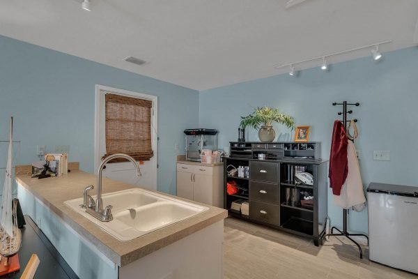 Kitchen interior with light blue walls, featuring a central island sink, cabinetry, and organized storage, highlighting a spacious and functional design ideal for a home in Windermere, FL.