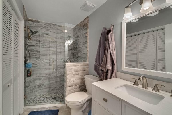Modern bathroom featuring a glass shower enclosure, white vanity with dual sinks, and stylish tile accents, part of the Windermere real estate listing at 1421 Crescent Lake Dr.