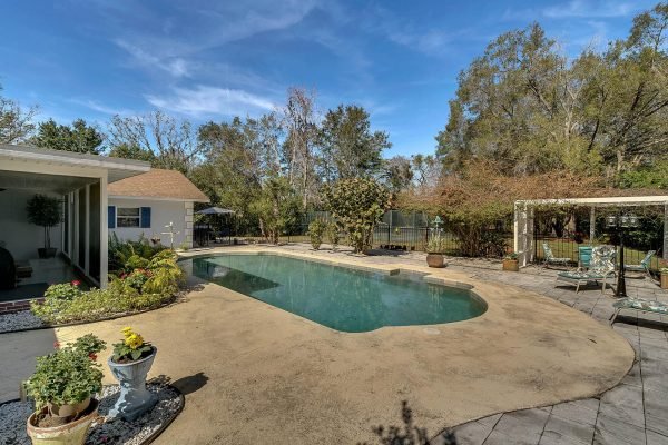 Pool area of 1421 Crescent Lake Dr, Windermere, FL, featuring a large swimming pool, surrounding patio, and lush landscaping, emphasizing the outdoor entertainment space of the estate.