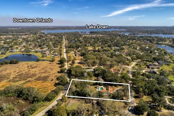 Aerial view of 1421 Crescent Lake Dr in Windermere, Florida, showcasing a spacious estate with a large pool and private tennis court, surrounded by lush greenery, near Lake Down and Downtown Orlando.