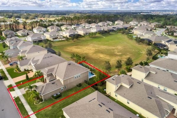 Aerial view of 15455 Sandfield Loop in Winter Garden, Florida, showcasing a spacious home with a premium lot, surrounded by residential properties, and a nearby open green area.