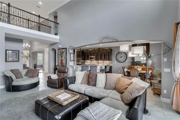 Spacious living room featuring modern furnishings, large sectional sofa, and elegant decor, with an open layout leading to a gourmet kitchen in a Winter Garden home.