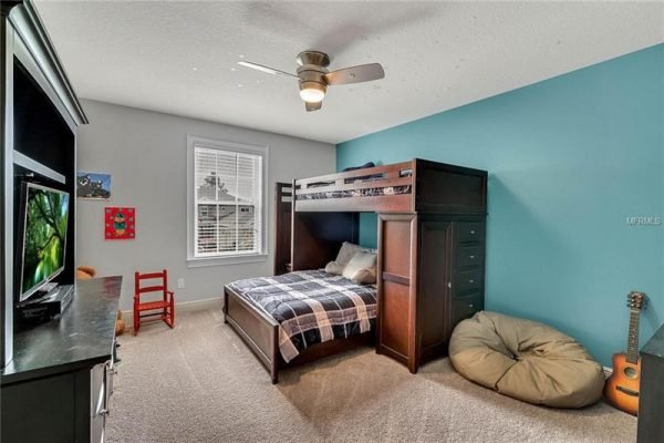 Child's bedroom featuring a lofted bed with storage, a cozy reading nook with a bean bag chair, and a guitar, accented by a blue wall and light gray decor.