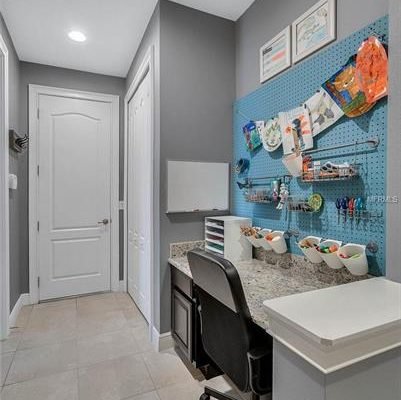 Home office space in Winter Garden, featuring a granite desk, organizational pegboard with art supplies, and modern decor, showcasing functionality and style in a family-friendly environment.