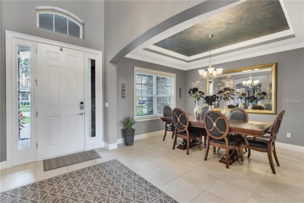 Elegant entryway of a home in Winter Garden, featuring a formal dining area with a large wooden table, decorative chandelier, and stylish decor, showcasing a welcoming atmosphere and modern design elements.