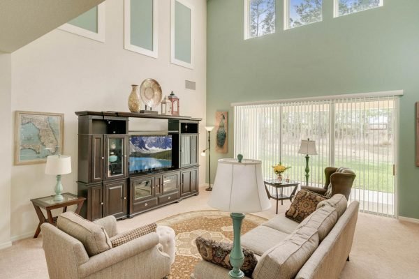 Spacious family room in 15522 Sandfield Loop, Winter Garden, FL, featuring high ceilings, large windows, and a cozy seating area with a TV unit and decorative accents.