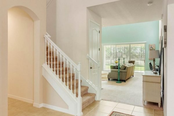 Foyer of 15522 Sandfield Loop in Winter Garden, featuring a staircase, open layout, and views of the great room with natural light and access to the backyard.