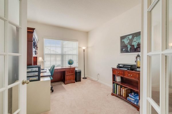 Home office with desk, globe, and wooden furniture, featuring natural light from window, within the 15522 Sandfield Loop property in Winter Garden, FL.