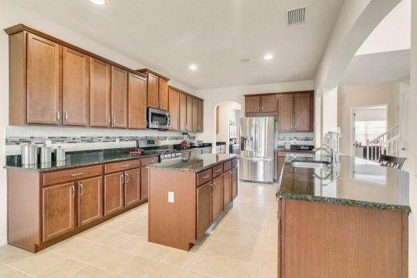 Modern kitchen in Winter Garden, FL, featuring dark wood cabinetry, granite countertops, stainless steel appliances, and an open layout, designed for entertaining and family gatherings.
