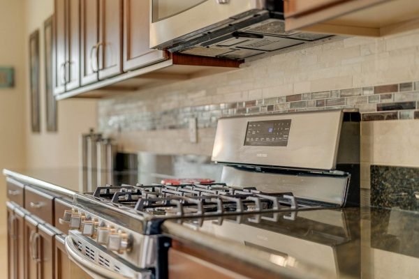 Modern kitchen featuring stainless steel gas stove, granite countertops, and elegant cabinetry, highlighting the spacious design of the home at 15522 Sandfield Loop, Winter Garden, FL.