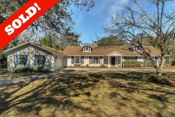 Sold sign overlay on a single-story home in Windermere, Florida, showcasing a spacious front yard with mature trees and a circular driveway.