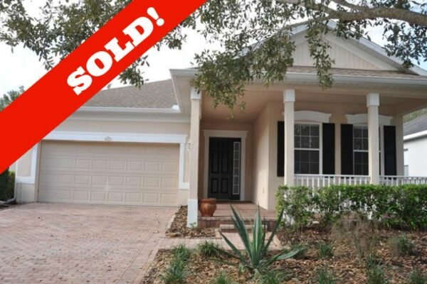 Sold home in Trilogy community, featuring a covered front porch, brick paver driveway, and landscaped yard, with a bold "SOLD!" overlay.
