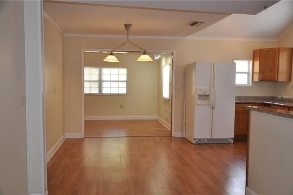 Interior view of the kitchen at 1006 Venetian Ave, Orlando, featuring hardwood flooring, a refrigerator, and a dining area with pendant lighting.