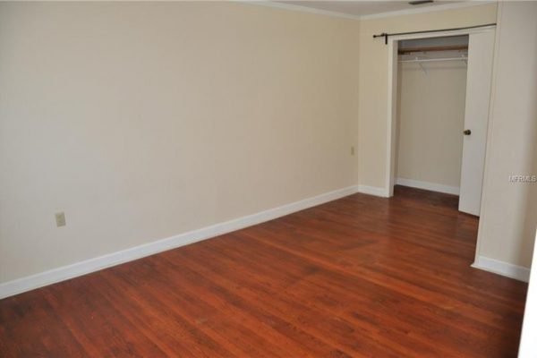 Spacious interior of a bedroom with hardwood floors, featuring a closet and neutral wall colors, highlighting the 1,539 sqft layout of the property at 1006 Venetian Ave, Orlando, FL.