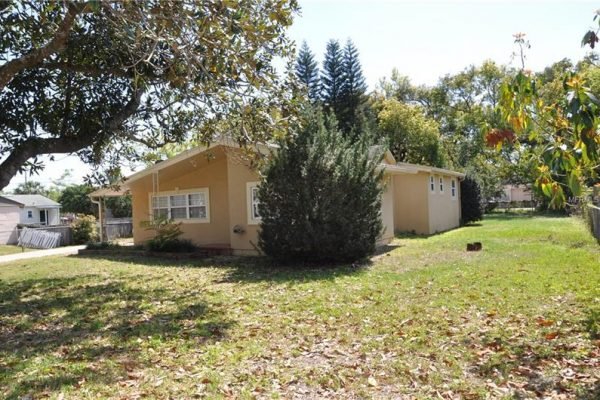 Single-story home at 1006 Venetian Ave, Orlando, FL, featuring a spacious yard with mature trees, surrounded by a fully fenced lot, showcasing its potential for buyers seeking homes in University Heights.