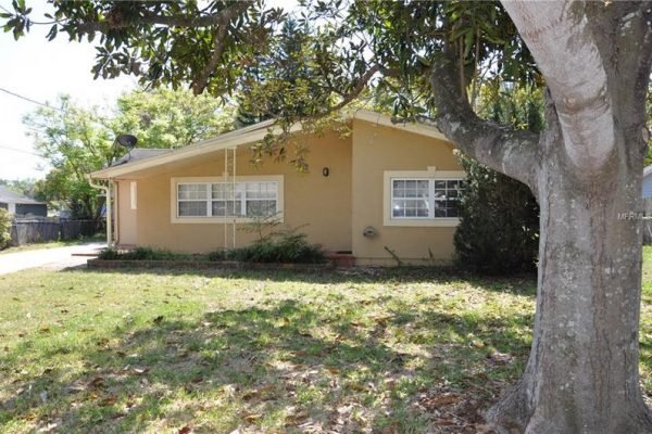 Single-story home at 1006 Venetian Ave, Orlando, FL, featuring a beige exterior, large front yard with mature trees, and multiple windows.