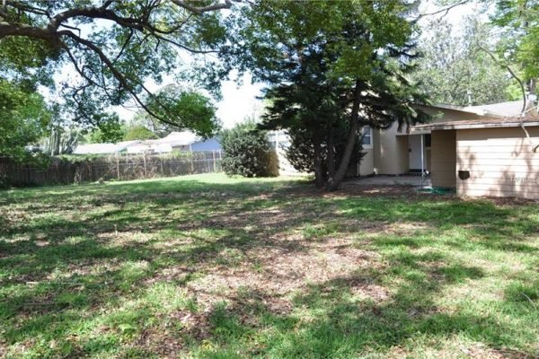 Large fenced backyard of 1006 Venetian Ave, Orlando, FL, featuring mature trees and ample green space, ideal for outdoor activities and privacy.