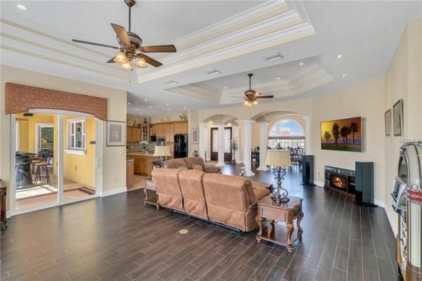 Spacious living room in Winter Garden home featuring elegant ceiling details, modern furnishings, and open concept design, highlighting the connection to the kitchen and outdoor views.
