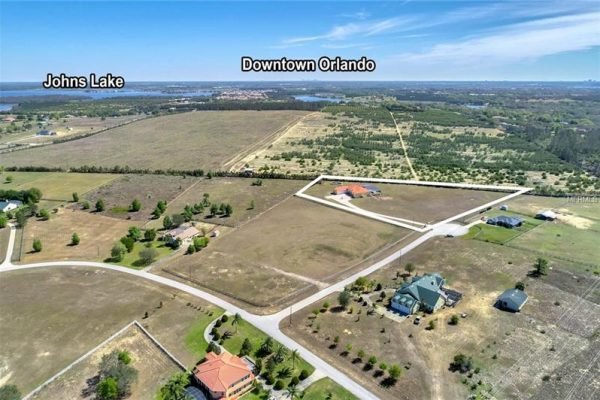 Aerial view of 11114 Romance Ct in Winter Garden, Florida, showcasing expansive land, nearby Johns Lake, and proximity to Downtown Orlando, highlighting the spacious lot and surrounding greenery.