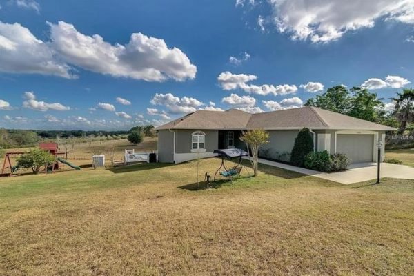 Single-family home at 11630 Flynn Ct in Winter Garden, FL, featuring a spacious lawn, playset, and scenic views, highlighting the property's 5-acre estate with two homes.